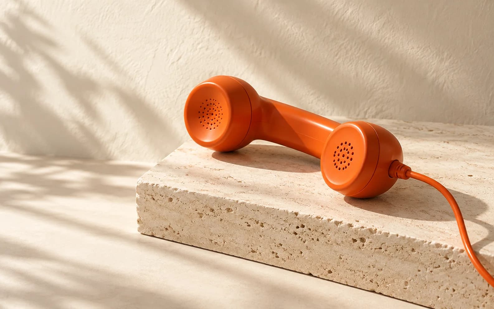 Orange telephone handset on an ivory stone pedestal
